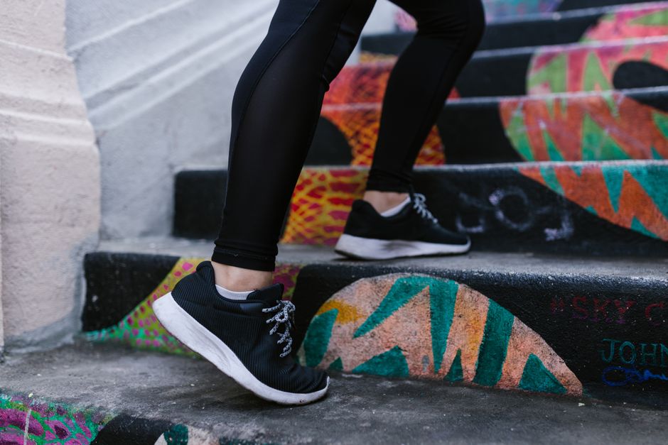 Close-up of a person walking up colorful graffiti stairs wearing sneakers.