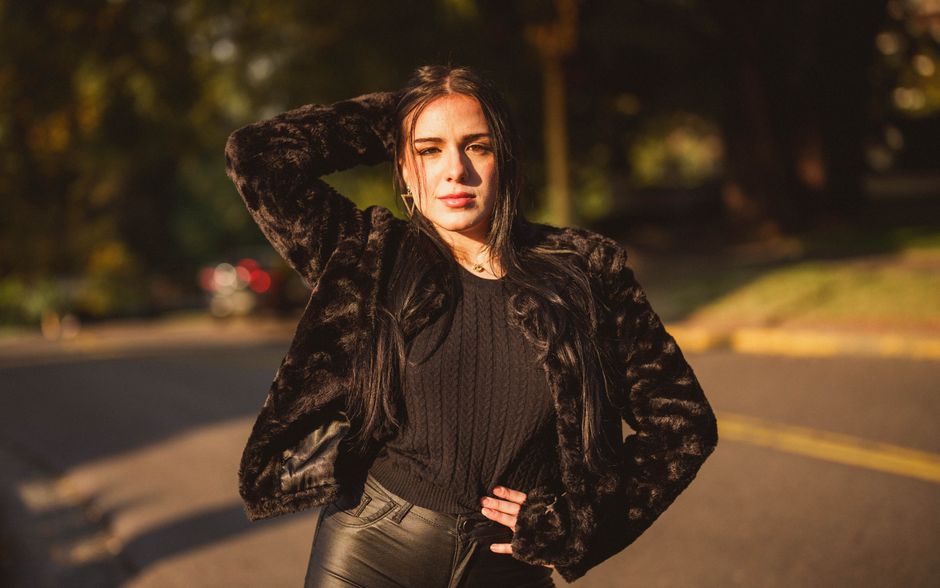 Portrait of a young woman with long hair posing confidently on a sunny day.