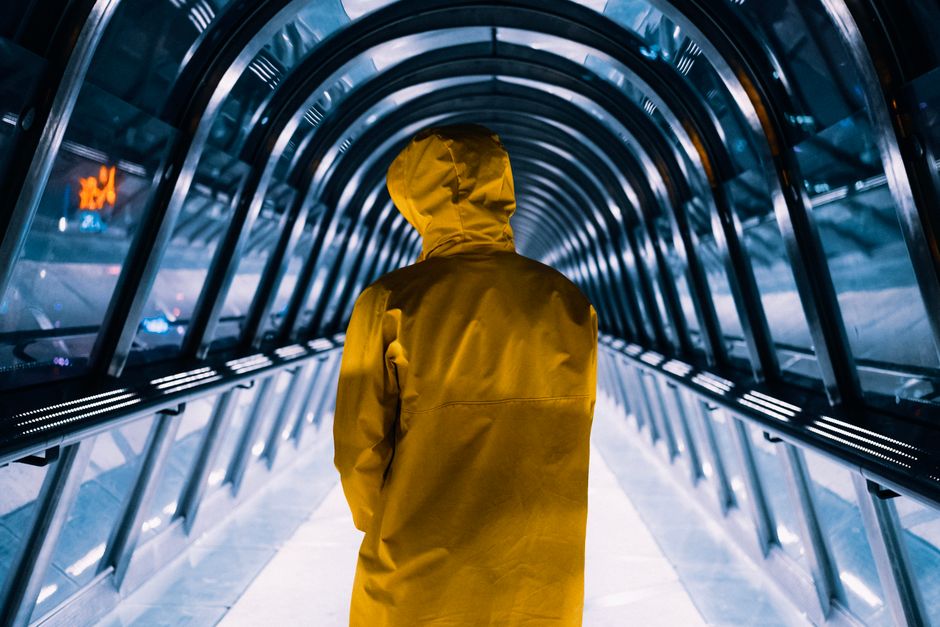 A person in a yellow jacket walks through a futuristic illuminated tunnel, showcasing urba
