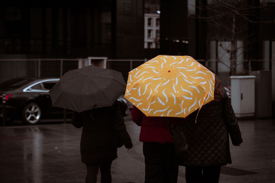City dwellers with umbrellas walking in Dublin on a rainy day, showcasing street life energy.