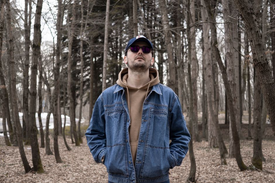 Man in jeans and sunglasses standing in an Istanbul forest, embracing nature.