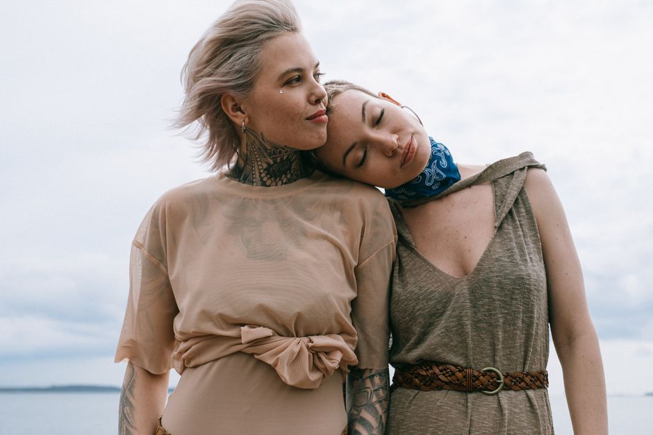 Two women share a tender moment by the seaside, epitomizing love and trust.