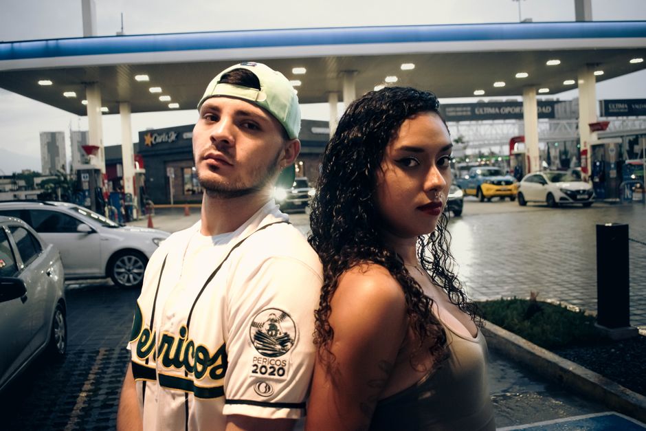 A couple poses confidently at an urban gas station in Puebla, Mexico, showcasing modern street style.