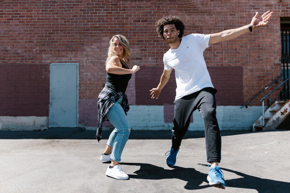 Dynamic duo performing street dance against a brick wall backdrop, showcasing energy and rhythm.