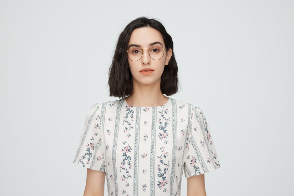 Portrait of a young woman in a floral dress and glasses, studio shot.