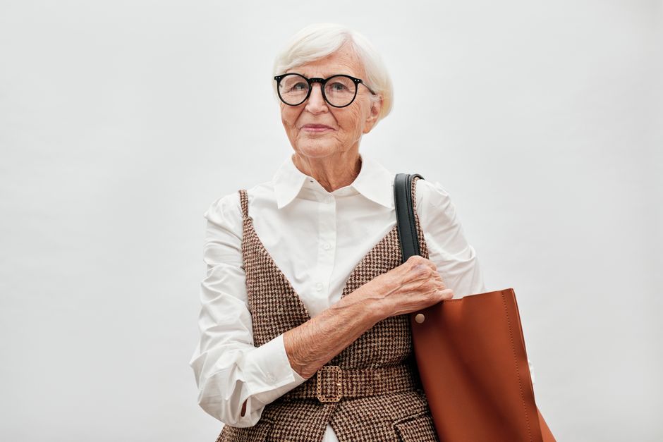 Elderly woman with eyeglasses and a stylish bag, exuding confidence and elegance.