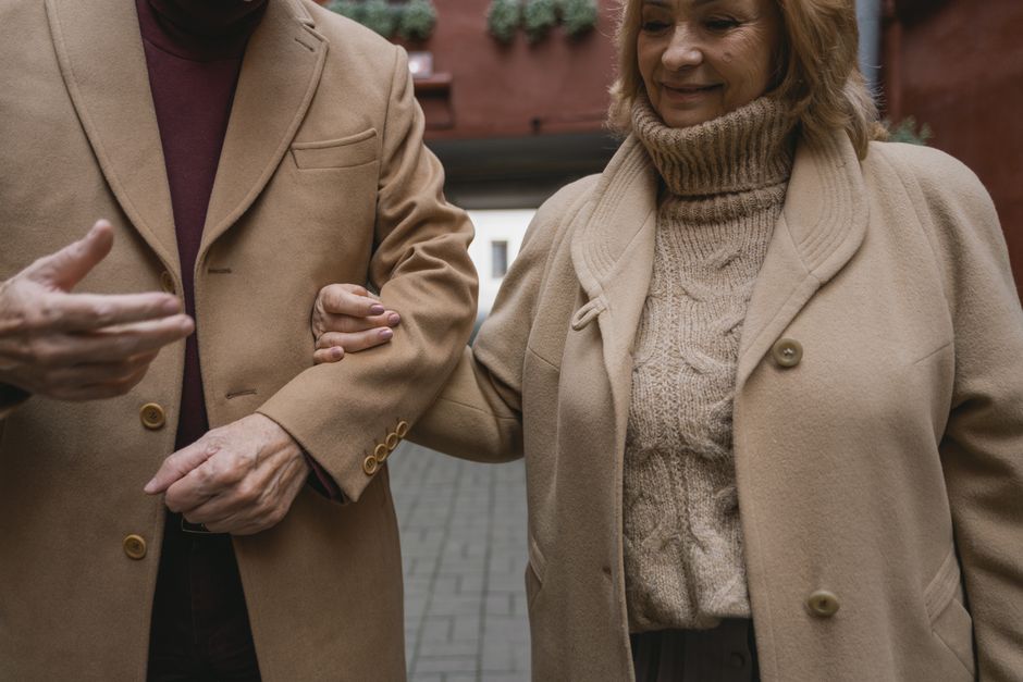 Senior couple walking arm in arm wearing cozy winter coats. Warm affection outdoors.