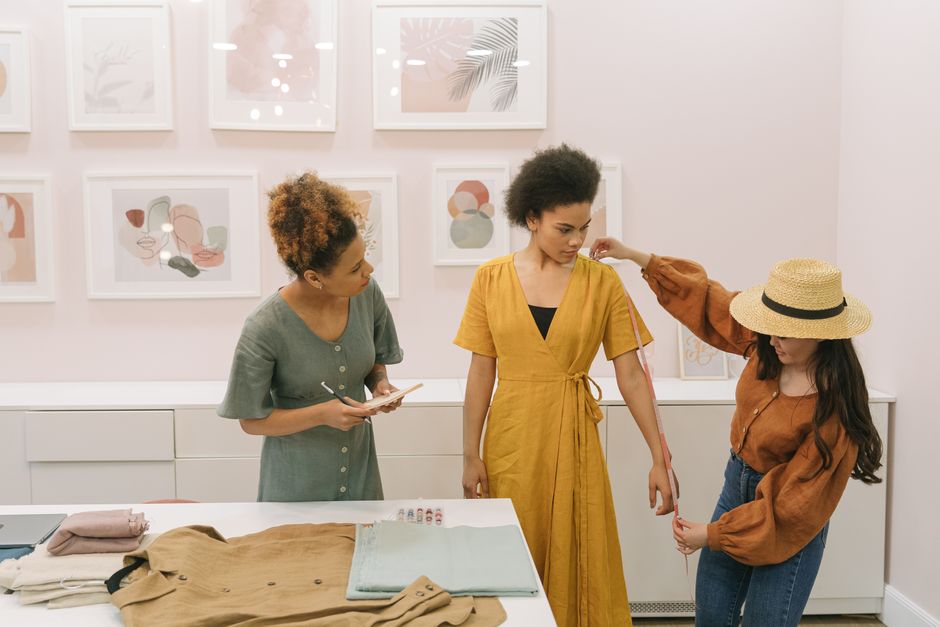 Three diverse women fashion designers collaborating in a stylish studio sewing session.