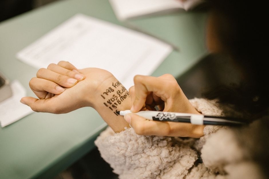 Close-up of a student writing cheat notes on their wrist during an exam.