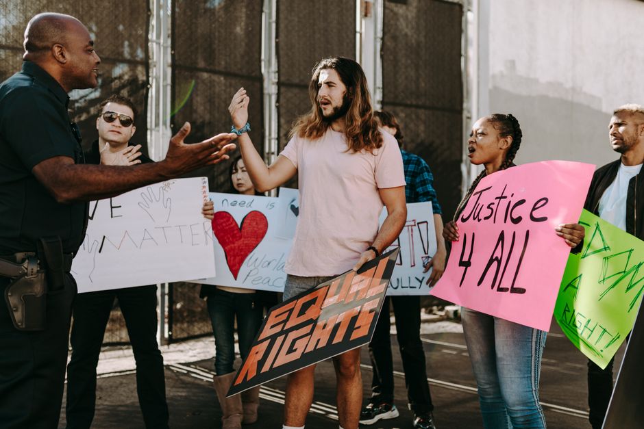 Diverse group of activists holding signs engaging with a policeman during a street protest.