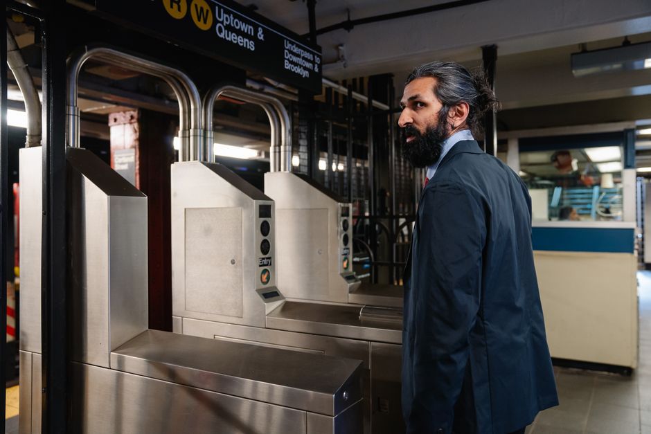 Businessman in formal attire entering a subway station using turnstile in urban setting.