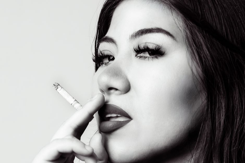 Artistic black and white portrait of a woman smoking a cigarette.
