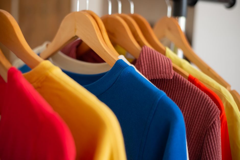 Vibrant clothing displayed on wooden hangers, showcasing fashion and color variety.