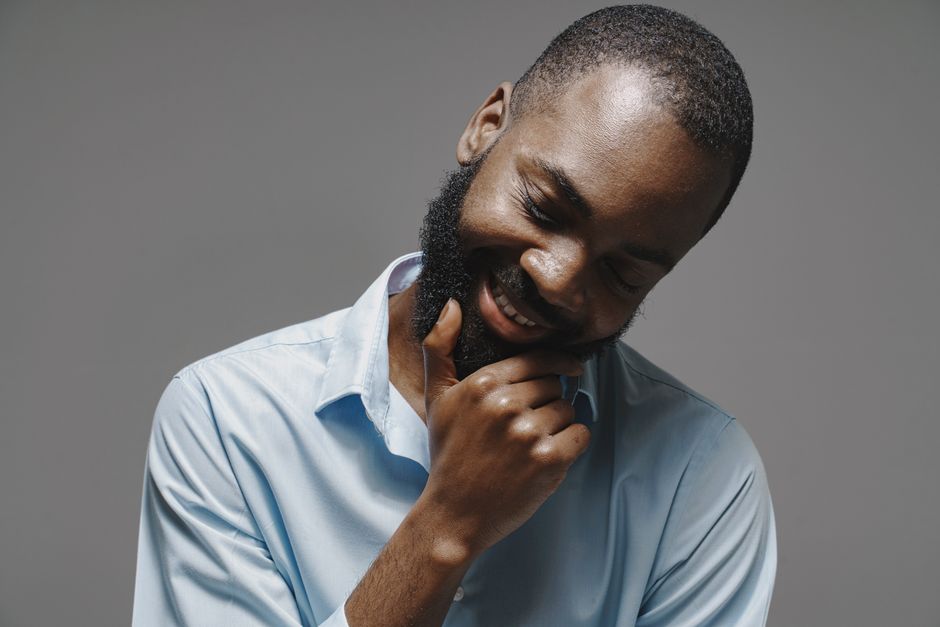 Portrait of a man with a beard, smiling with a thoughtful expression in a white dress shir