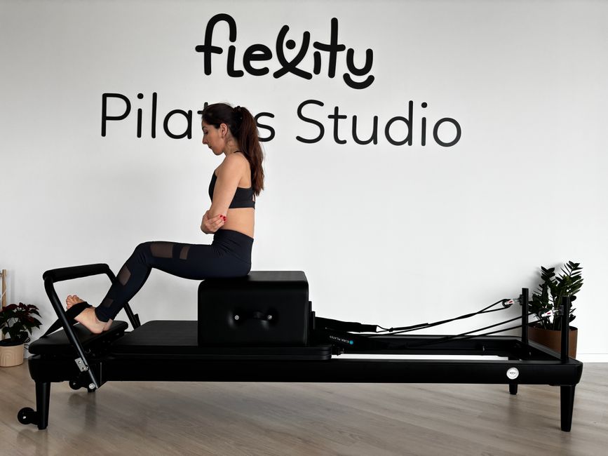 Focused woman practicing on a Pilates reformer in a modern studio.