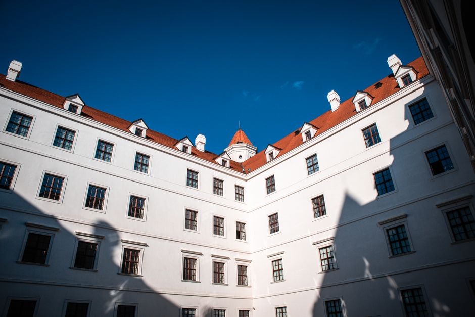 Elegant historic building with a white facade, red roof, and clear blue sky. Captured in daylight.