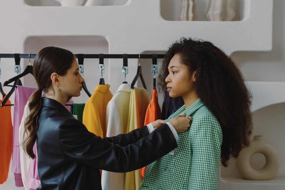 Fashion stylist adjusts outfit for model in chic boutique.