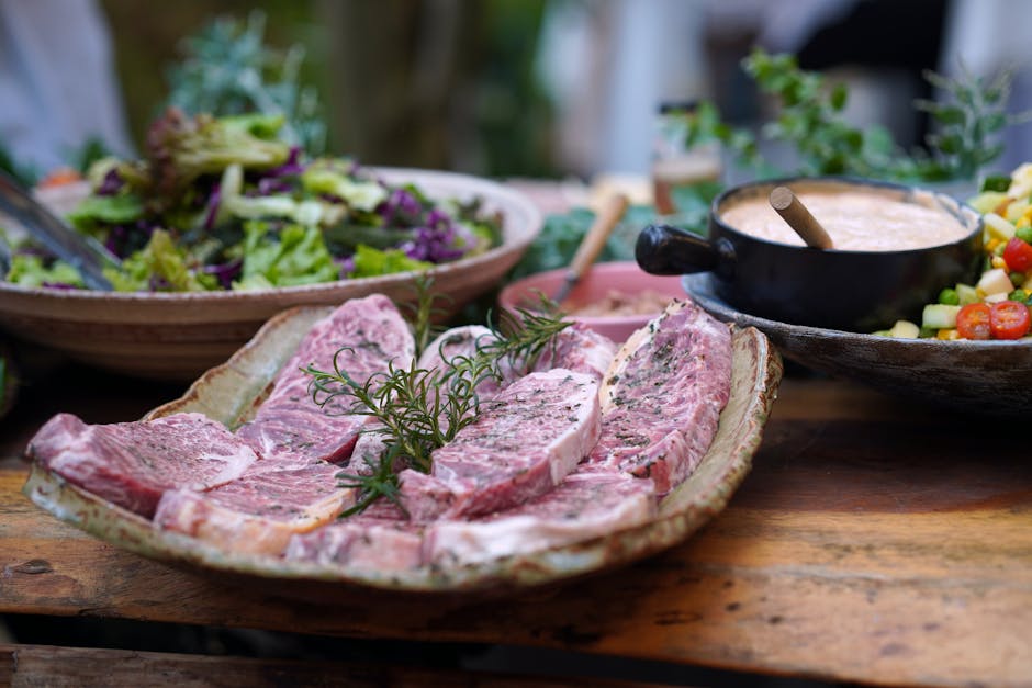 A close-up view of gourmet raw beef steaks on a platter, garnished with fresh rosemary, ready for cooking.