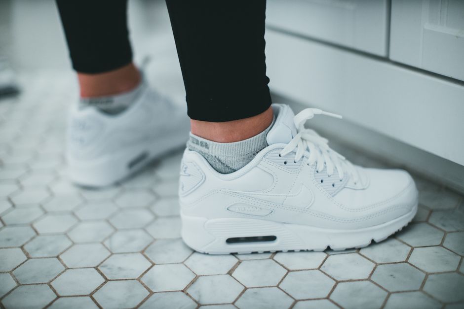 Close-up of white sneakers on hexagonal tiled floor, perfect for fashion or lifestyle themes.