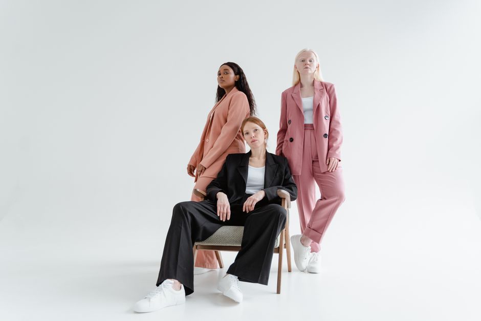 Diverse group of women posing in modern suits on a white background.