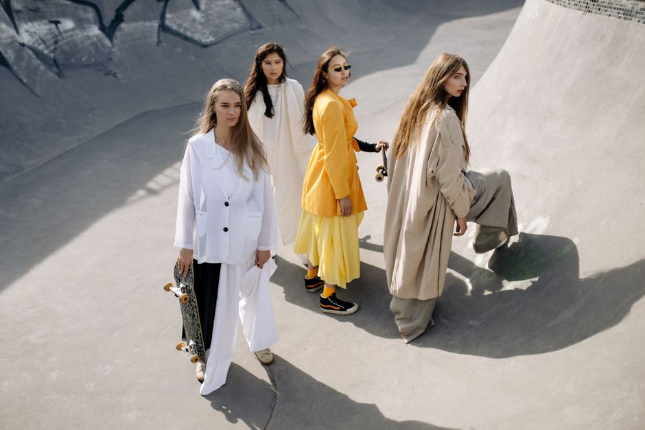 Stylish women posing creatively at a skate park in modern outfits.