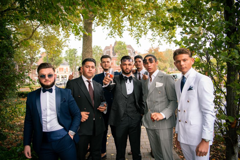 A group of stylish groomsmen in suits posing outdoors at a wedding ceremony, exuding elegance.