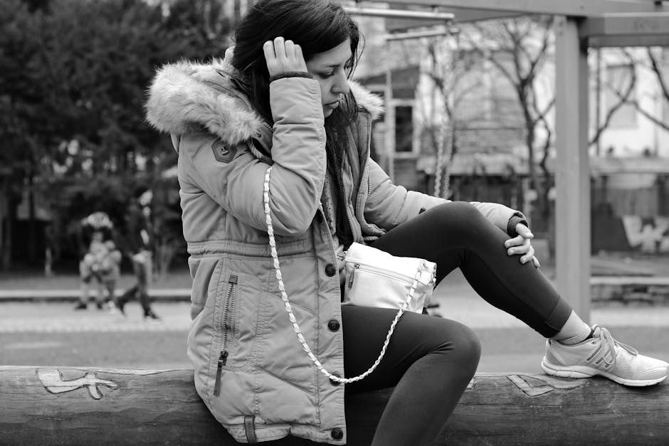 Black and white photo of woman in park, wearing winter coat and leggings.
