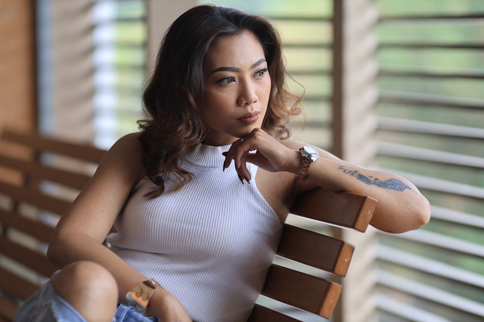 Thoughtful woman sitting indoors on a wooden bench, gazing outside.