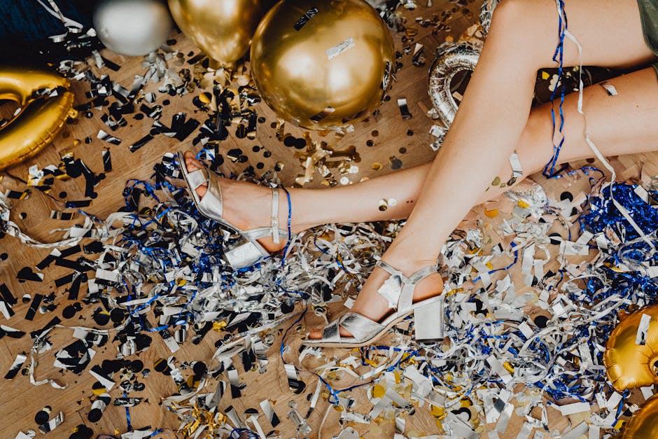 Elegant legs amidst a colorful mix of confetti and balloons, capturing a vibrant celebration aftermath.