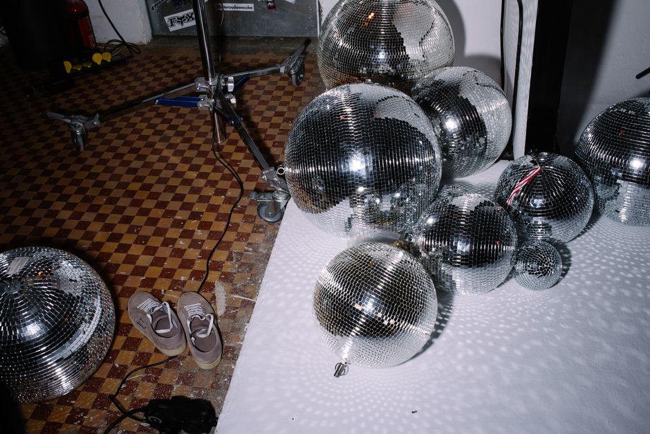 Disco balls scattered on a checkered floor, creating a reflective ambiance.