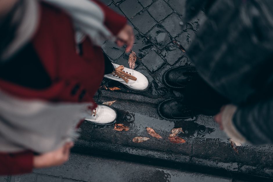 View of fashionable shoes on a wet pavement with autumn leaves, showcasing urban street st