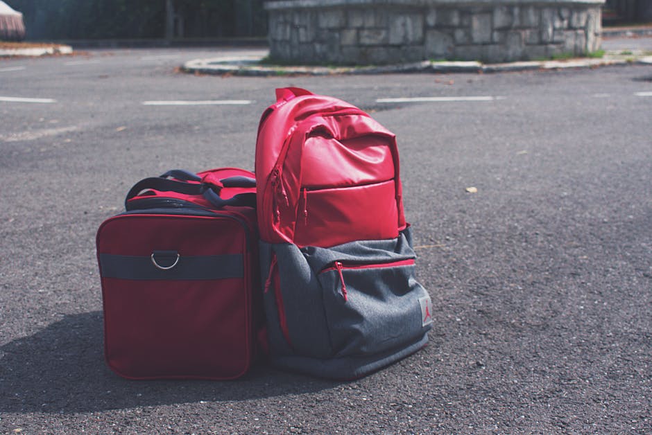 Red backpack and matching bag on asphalt, perfect for travel themes.