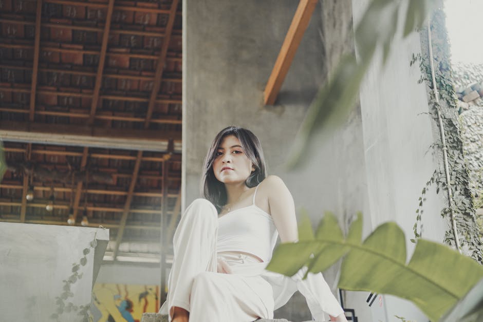 Woman in white attire sitting indoors with a modern and relaxed ambiance.