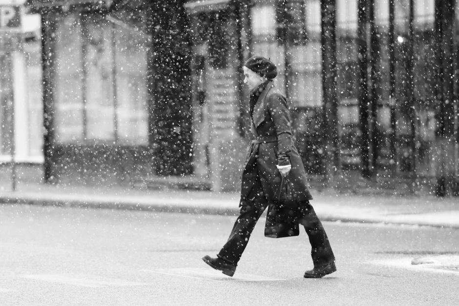 Black and white photo of a woman walking in the snow in Jönköping, Sweden.