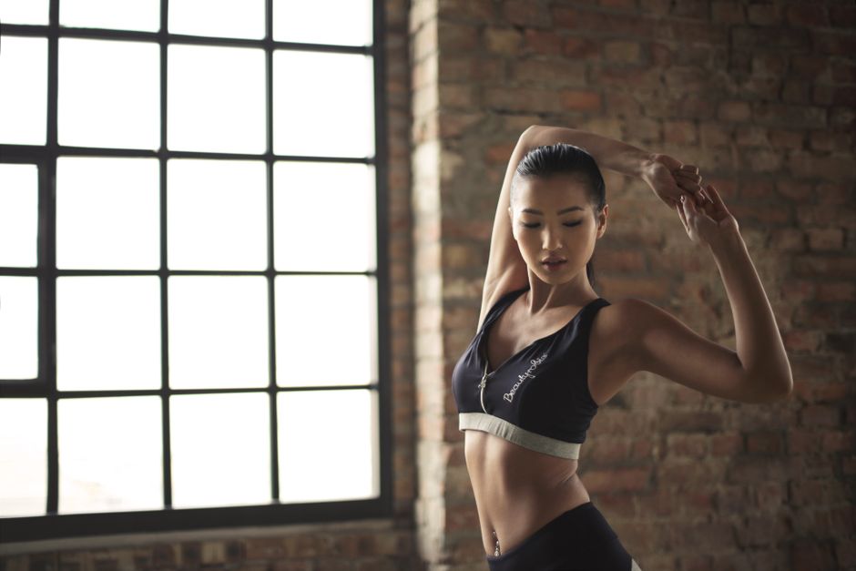 A woman practicing yoga indoors, highlighting strength and flexibility against a brick wall backdrop.