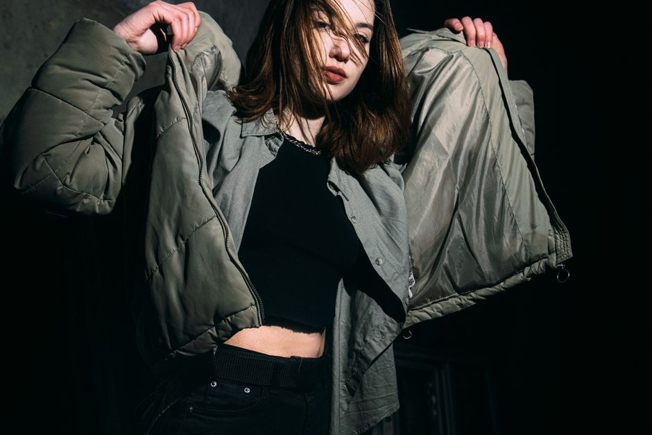 Young woman adjusting her winter jacket in a fashion studio setting.