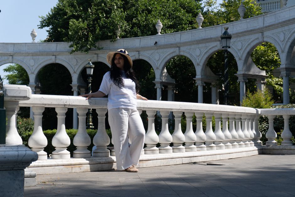 A woman in casual attire enjoys a sunny day at a historic garden in Baku, Azerbaijan.